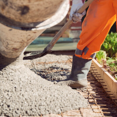 Concrete pouring during commercial concreting floors of building Worker with gum boots spreading ready mix concrete